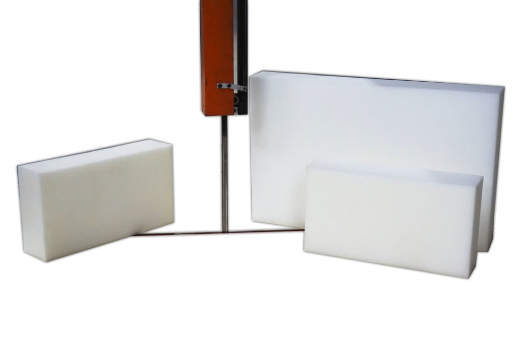 Precision-cut white foam blocks beside a vertical cutting machine