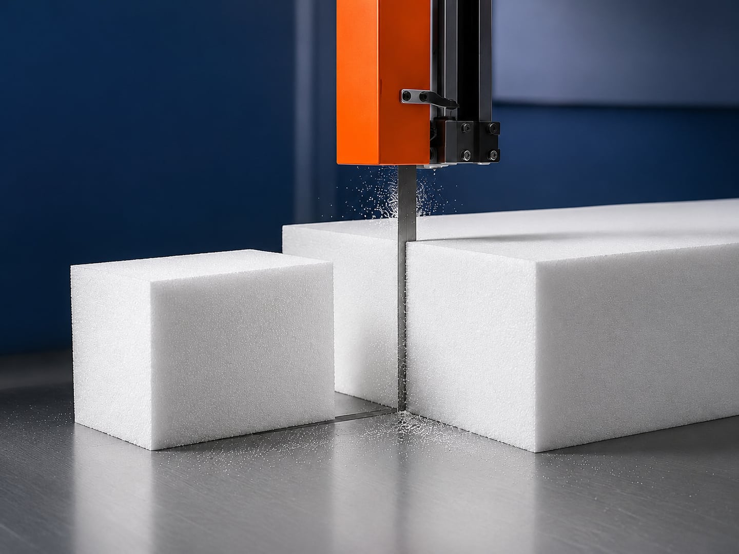 White protective foam blocks being precision-cut on an industrial band saw
