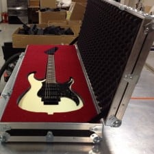 White electric guitar fitted into a red-lined case